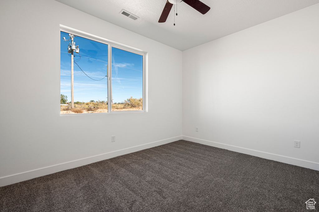 Spare room with ceiling fan and dark carpet