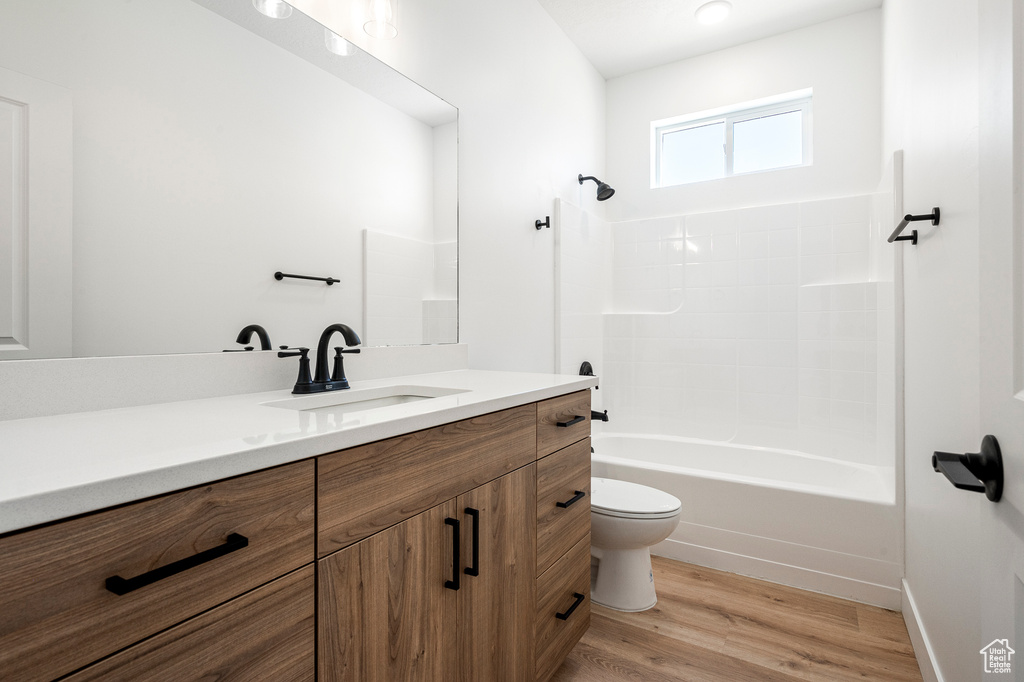 Full bathroom with toilet, shower / bathing tub combination, hardwood / wood-style floors, and vanity