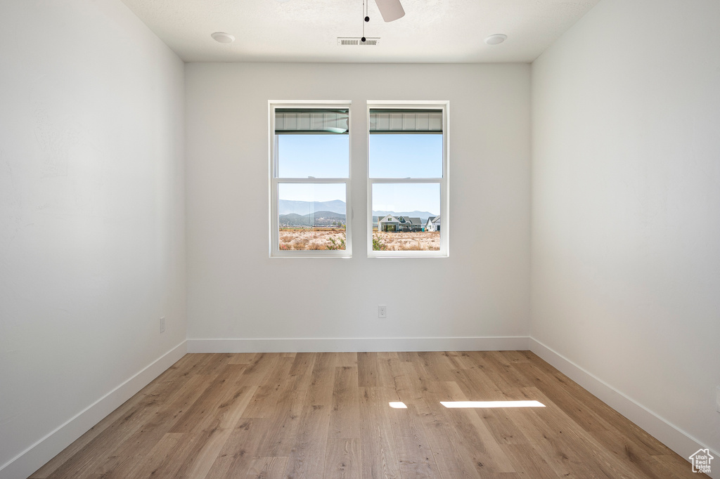 Empty room featuring a mountain view, light hardwood / wood-style flooring, and ceiling fan