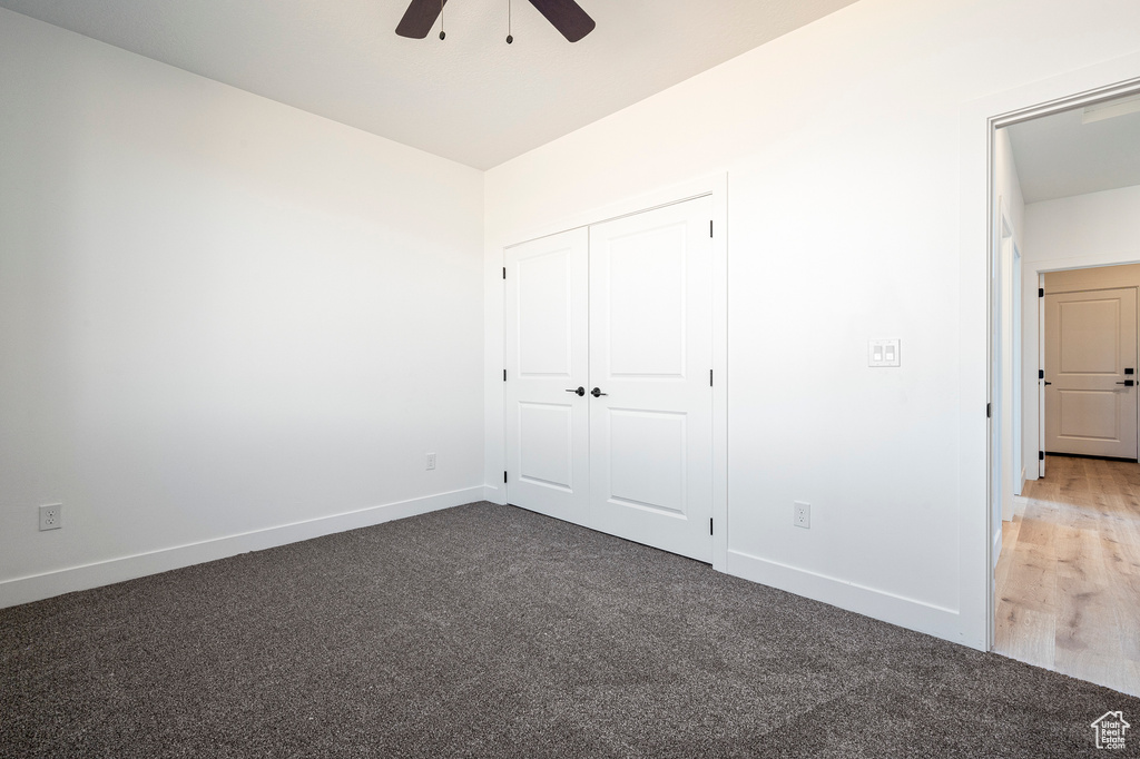 Unfurnished bedroom featuring a closet, dark hardwood / wood-style floors, and ceiling fan