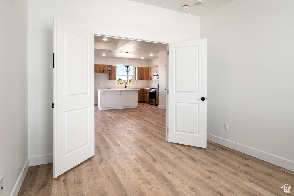 Kitchen featuring sink, decorative light fixtures, gas stove, and light hardwood / wood-style floors