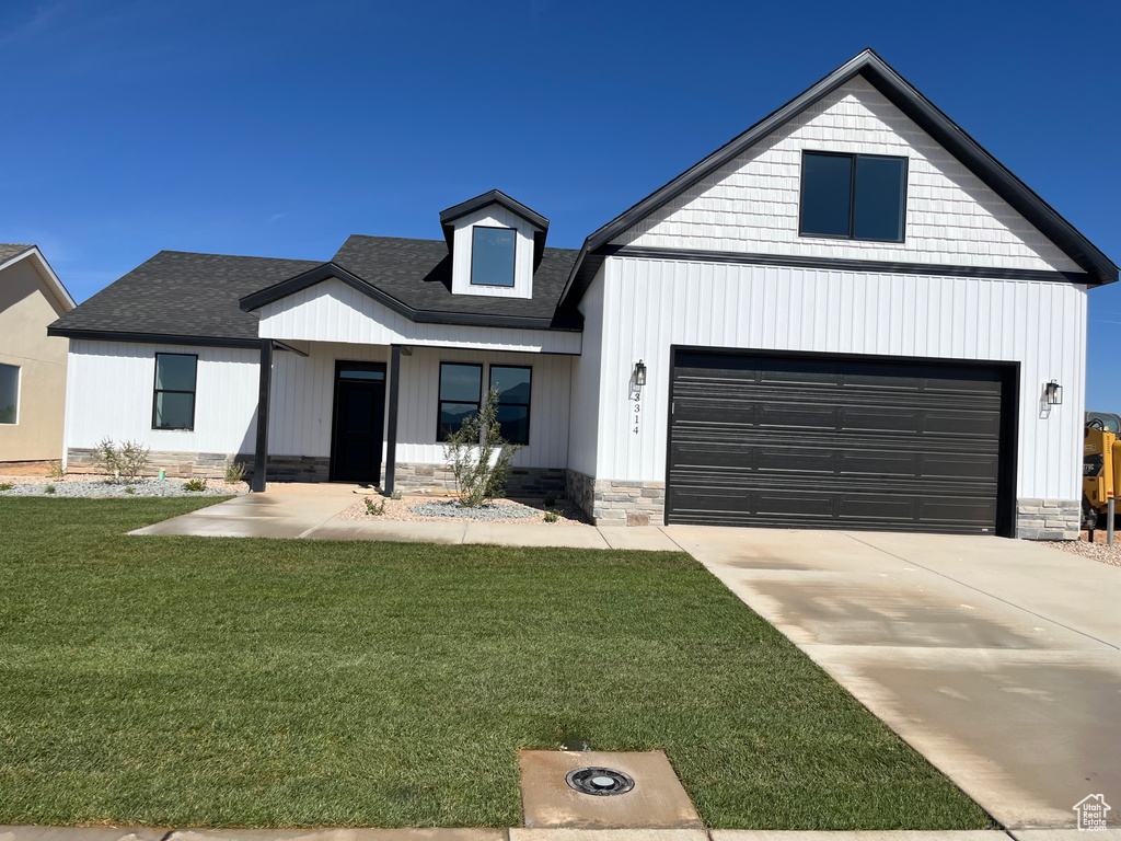 Modern farmhouse style home featuring a front lawn and a garage