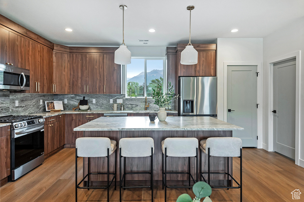 Kitchen featuring tasteful backsplash, stainless steel appliances, light hardwood / wood-style flooring, and a kitchen island