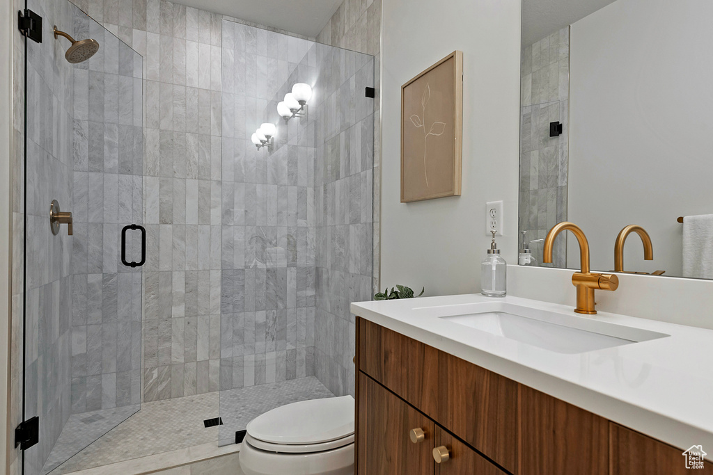 Bathroom featuring toilet, vanity, and a shower with shower door