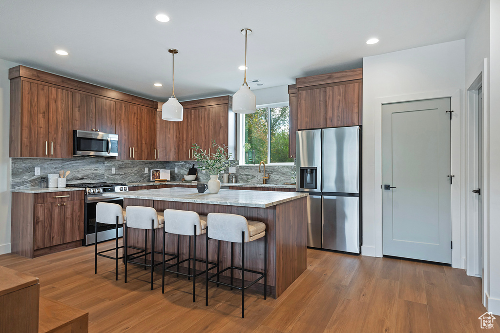 Kitchen featuring tasteful backsplash, stainless steel appliances, a kitchen island, and hardwood / wood-style floors