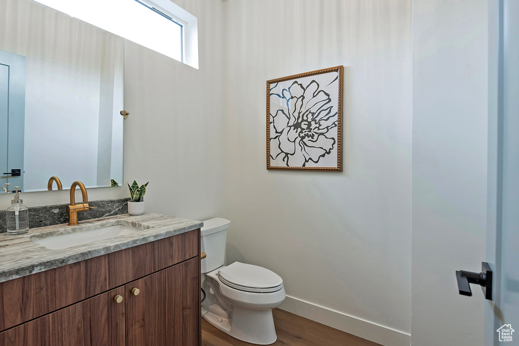 Bathroom with toilet, vanity, and hardwood / wood-style flooring