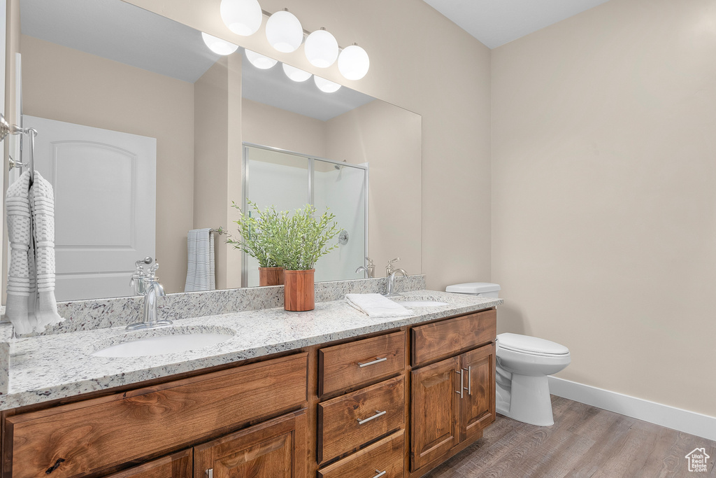 Bathroom featuring toilet, dual bowl vanity, and wood-type flooring