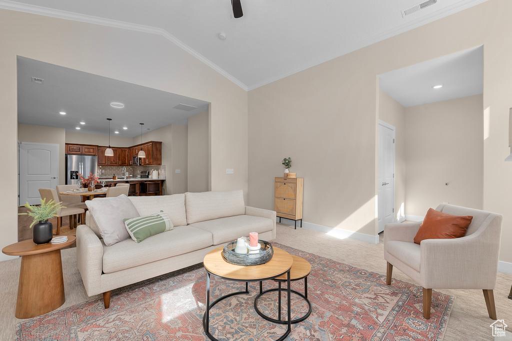 Carpeted living room with lofted ceiling and ornamental molding