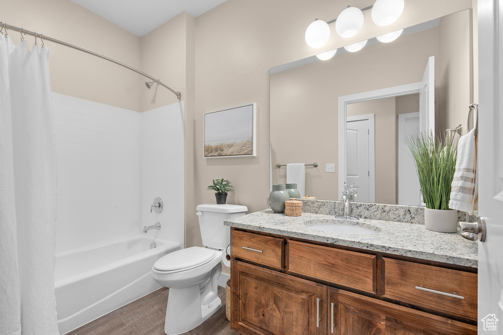 Full bathroom with shower / tub combo with curtain, vanity, toilet, and hardwood / wood-style flooring