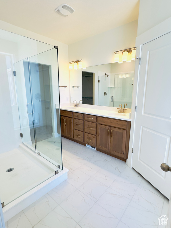 Bathroom featuring a shower with shower door, double vanity, and tile patterned flooring