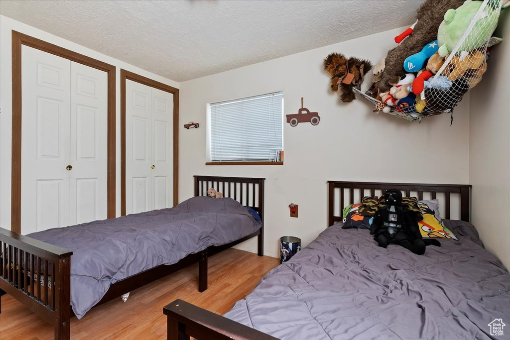 Bedroom with multiple closets, light hardwood / wood-style flooring, and a textured ceiling