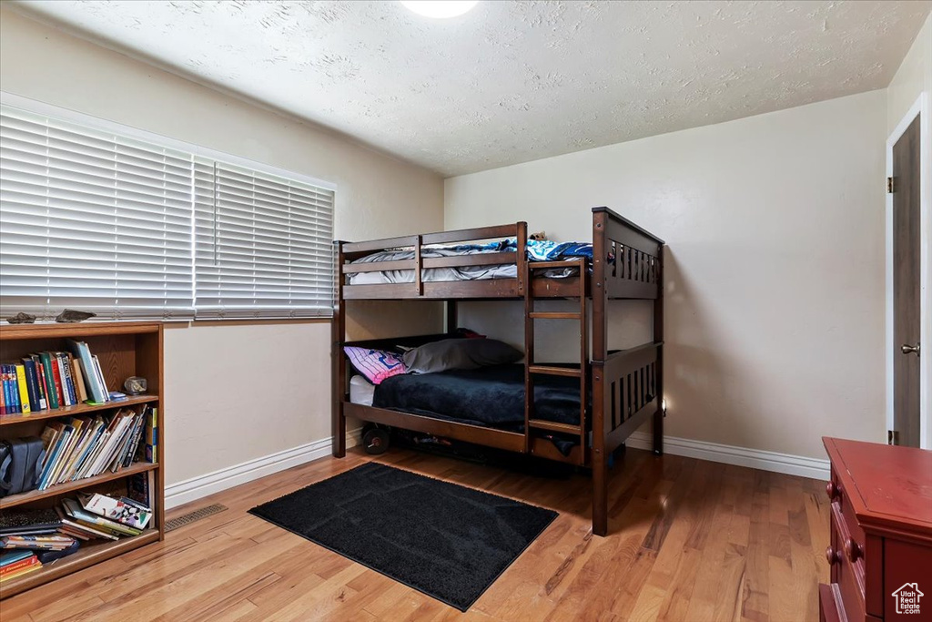 Bedroom with light hardwood / wood-style flooring and a textured ceiling