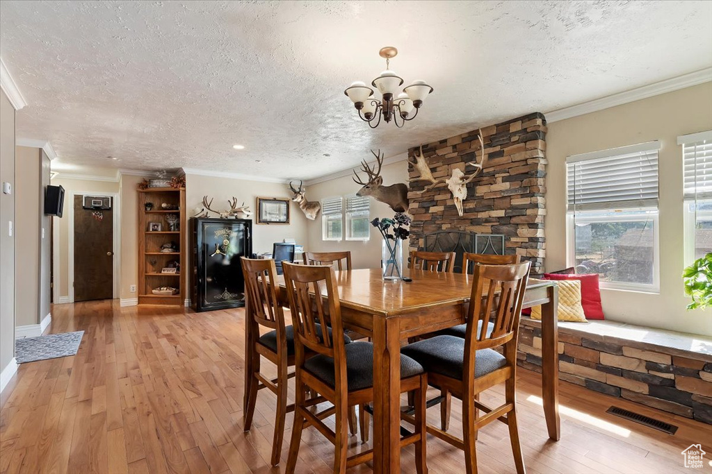 Dining area with light hardwood / wood-style flooring, a textured ceiling, and plenty of natural light