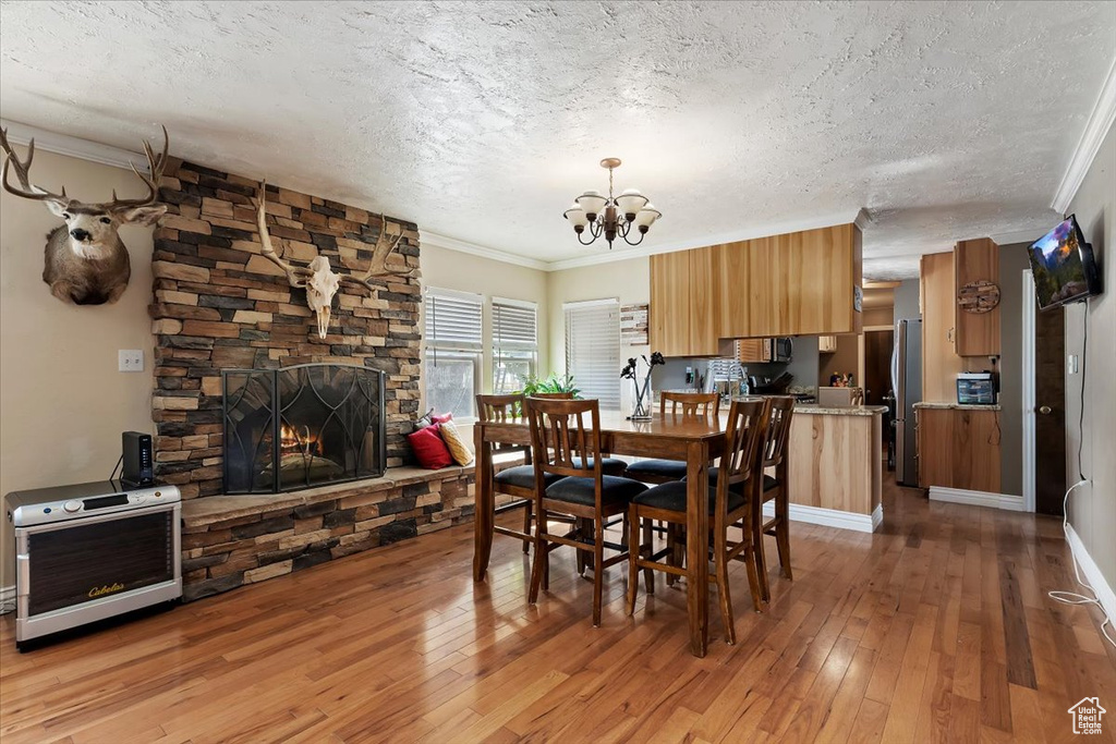 Dining room featuring a notable chandelier, a fireplace, a textured ceiling, and hardwood / wood-style flooring