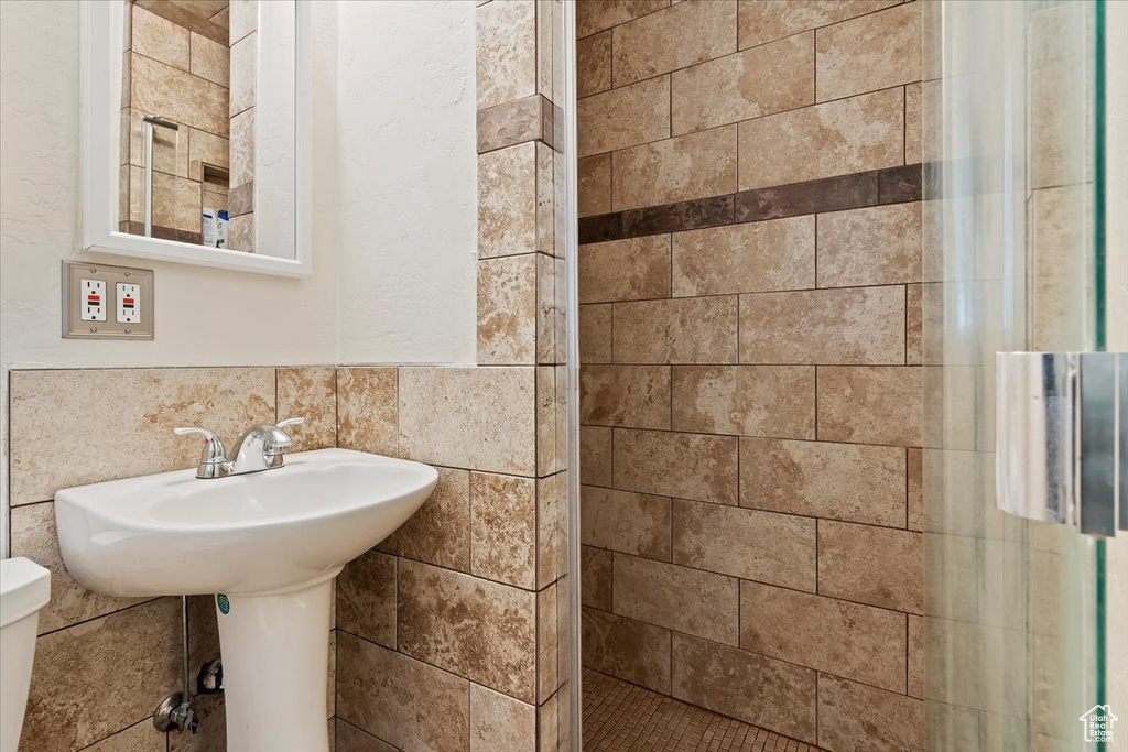 Bathroom featuring tasteful backsplash, tile walls, toilet, and tiled shower