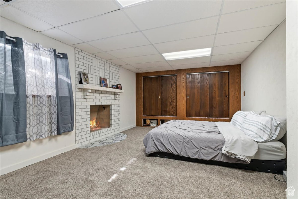 Bedroom featuring a fireplace, a drop ceiling, and carpet floors