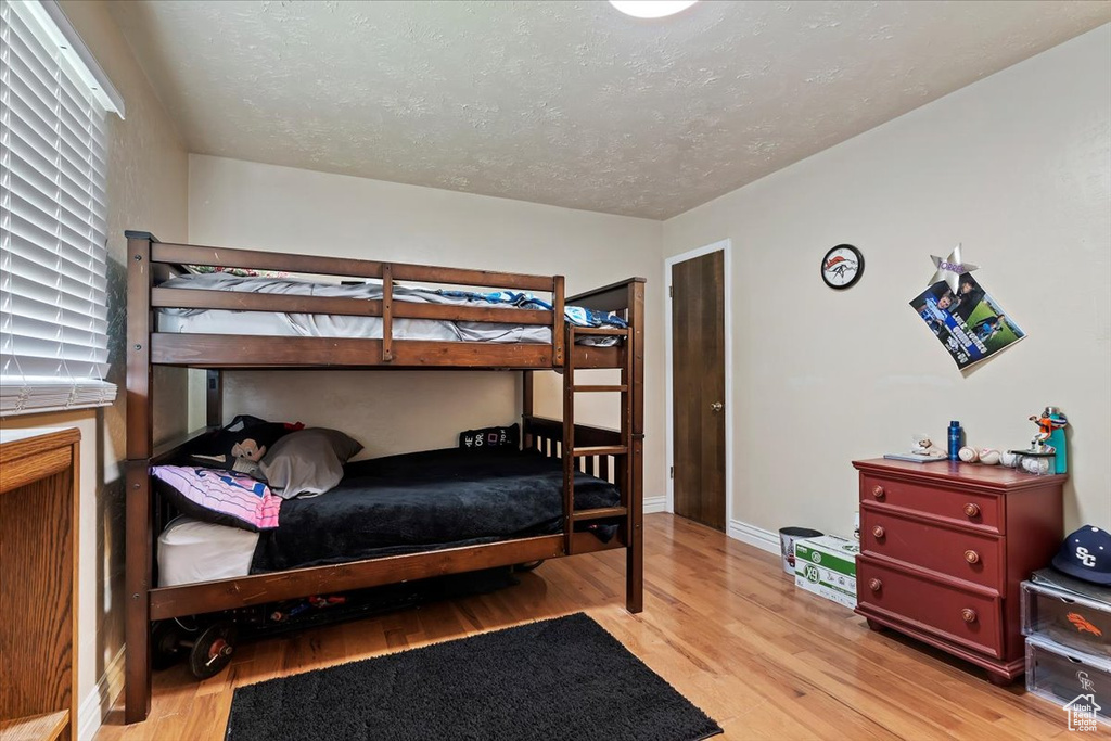 Bedroom featuring a textured ceiling, multiple windows, and light hardwood / wood-style floors