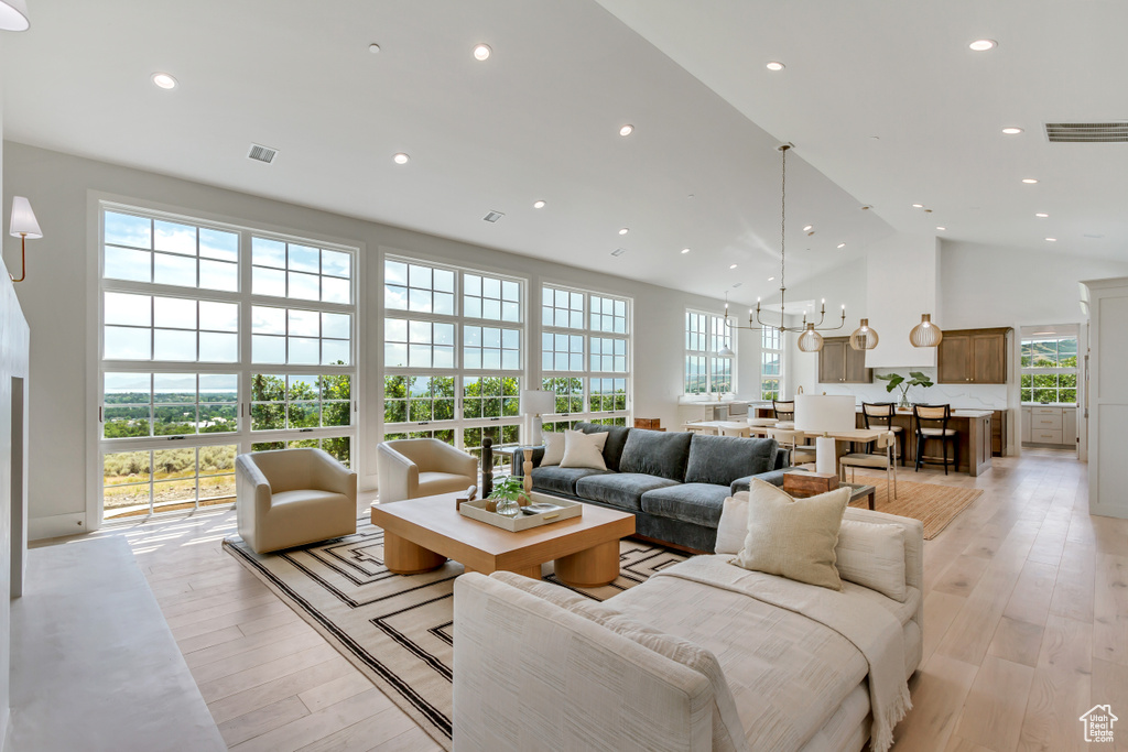 Living room featuring a notable chandelier, high vaulted ceiling, and light hardwood / wood-style flooring