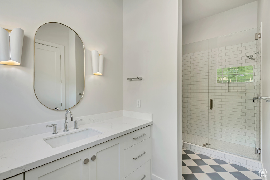 Bathroom featuring a shower with shower door, vanity, and toilet