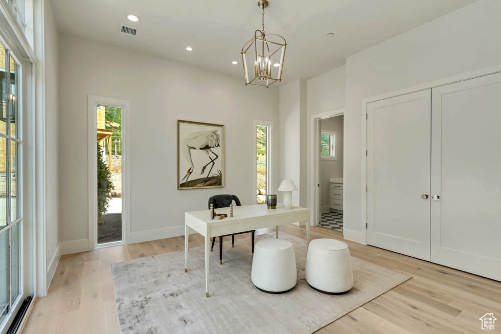 Office with light wood-type flooring and a chandelier