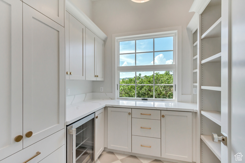 Interior space featuring light stone counters, white cabinets, and beverage cooler