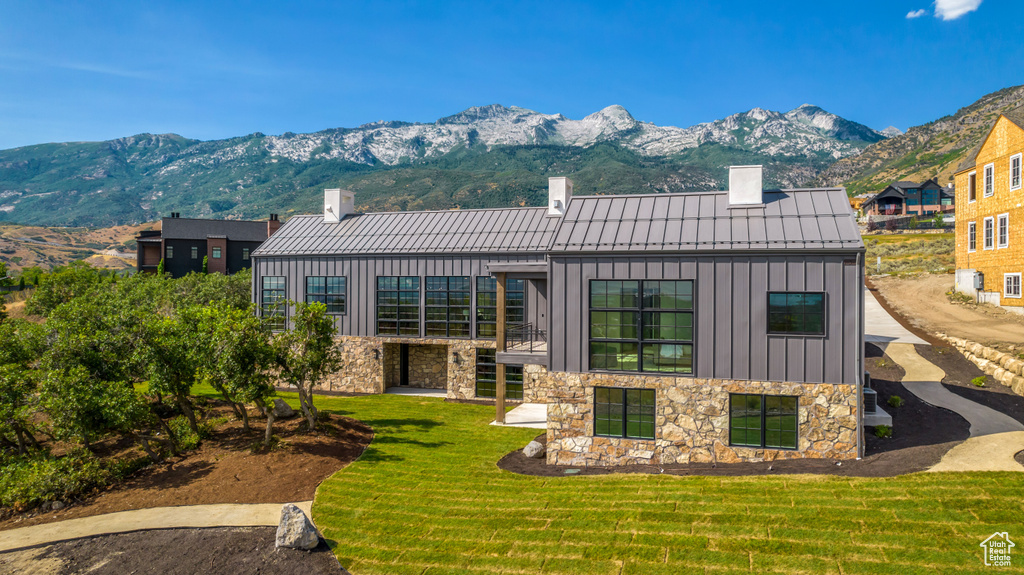 Rear view of house with a mountain view and a yard