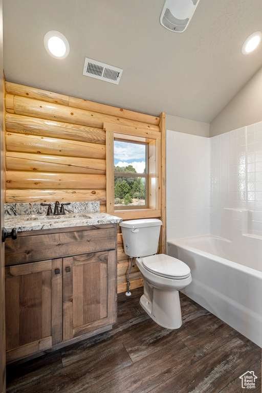 Full bathroom featuring lofted ceiling, hardwood / wood-style flooring, tub / shower combination, toilet, and vanity