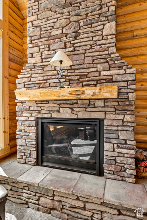 Room details with log walls and a stone fireplace