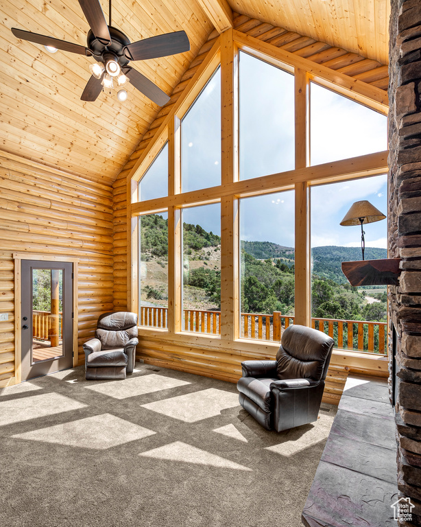 Sunroom with ceiling fan, a mountain view, lofted ceiling with beams, and wood ceiling