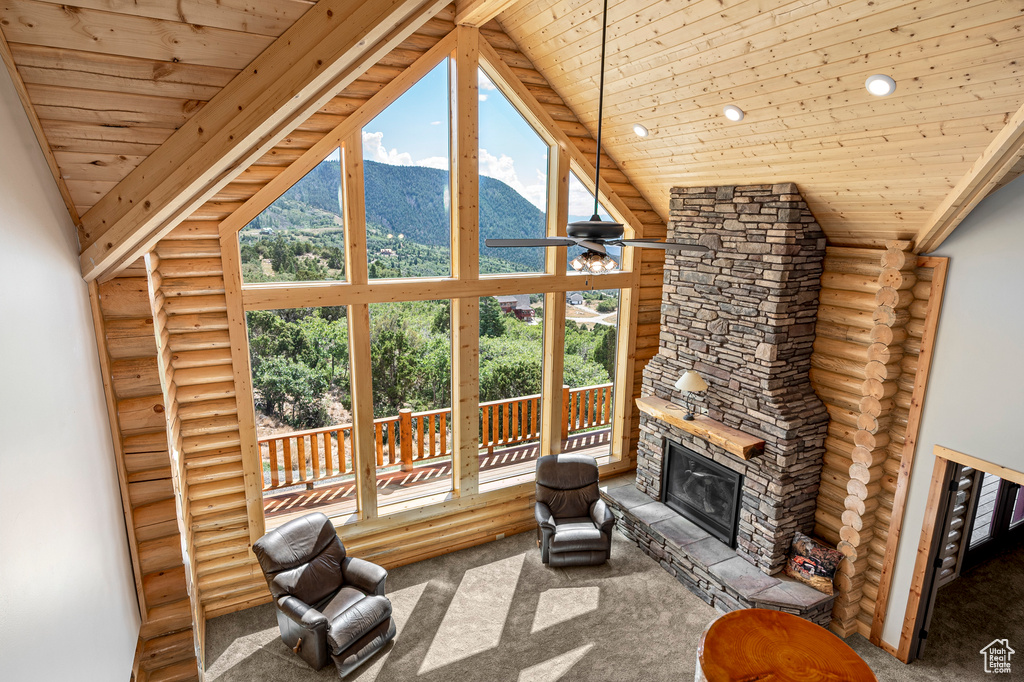 Unfurnished living room with rustic walls, high vaulted ceiling, a fireplace, and a mountain view