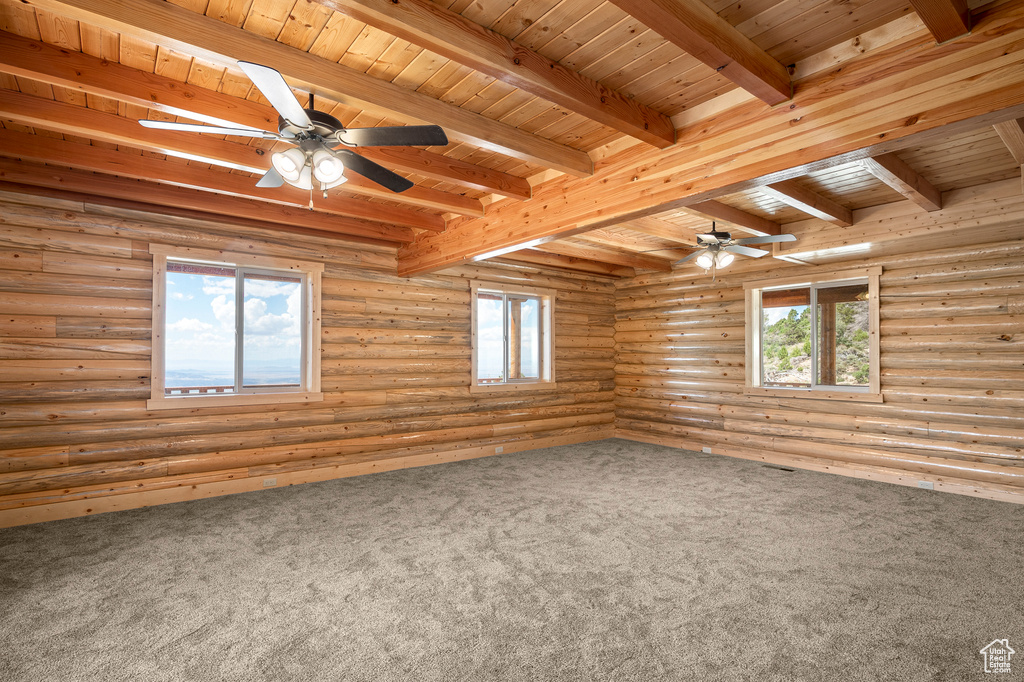 Unfurnished room with carpet floors, log walls, beamed ceiling, and wooden ceiling