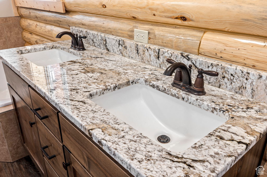 Bathroom with hardwood / wood-style floors, rustic walls, and double vanity