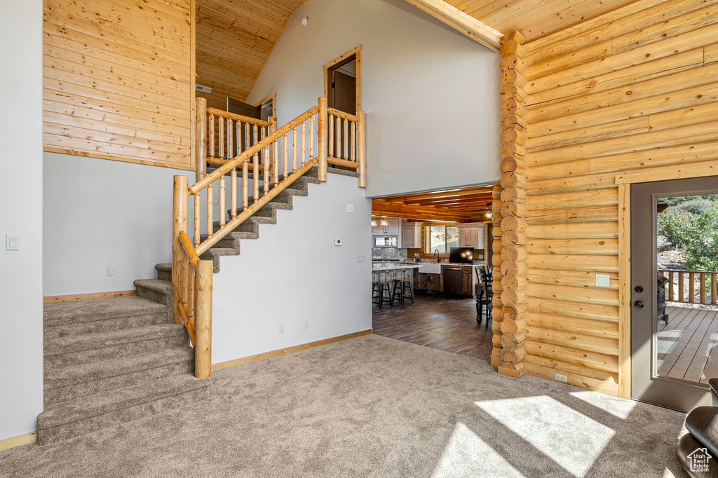 Unfurnished living room featuring wooden ceiling, wood-type flooring, high vaulted ceiling, and log walls