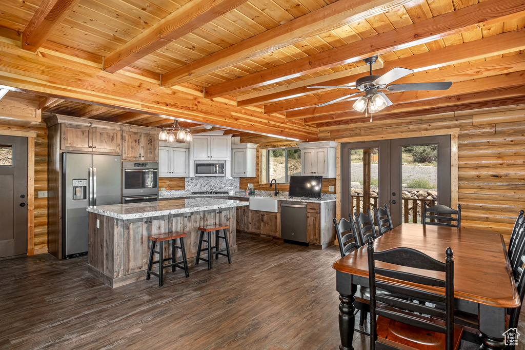 Kitchen featuring wood ceiling, rustic walls, stainless steel appliances, and a kitchen island