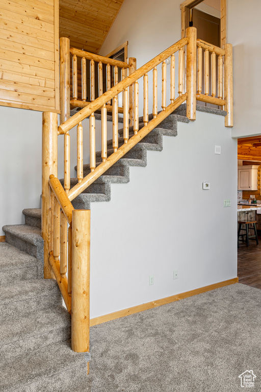 Stairs with wooden ceiling, high vaulted ceiling, and carpet floors