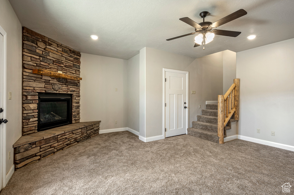 Unfurnished living room with ceiling fan, a fireplace, and light carpet