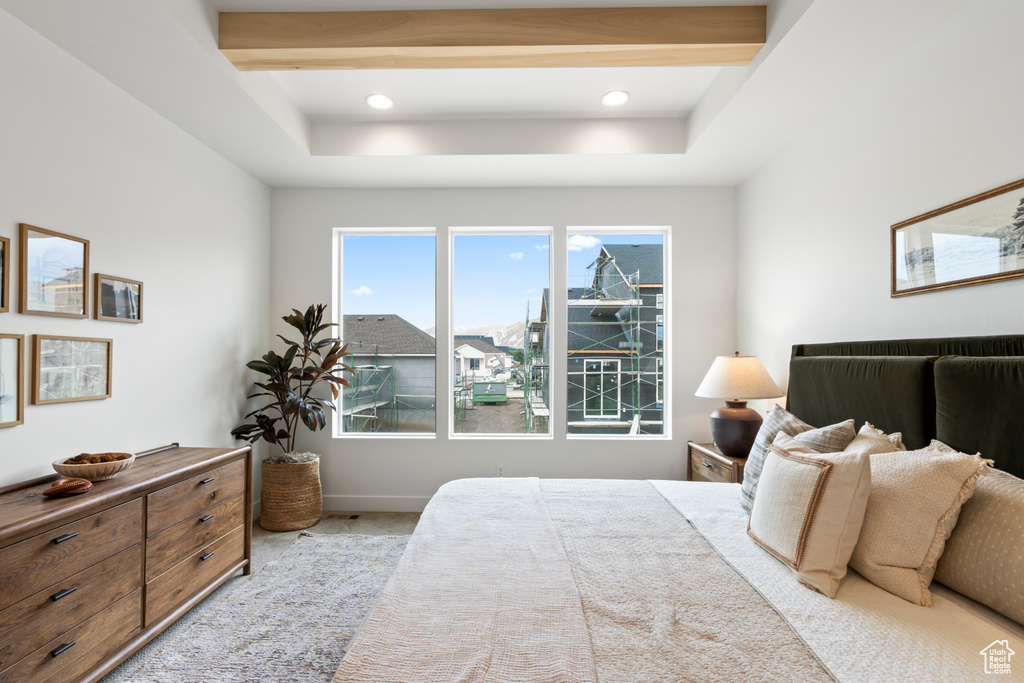 Carpeted bedroom featuring beamed ceiling and a raised ceiling