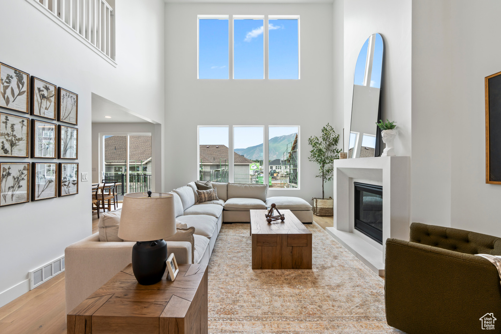 Living room with light hardwood / wood-style flooring and a high ceiling