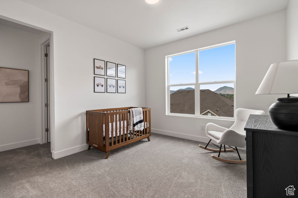 Carpeted bedroom featuring a crib