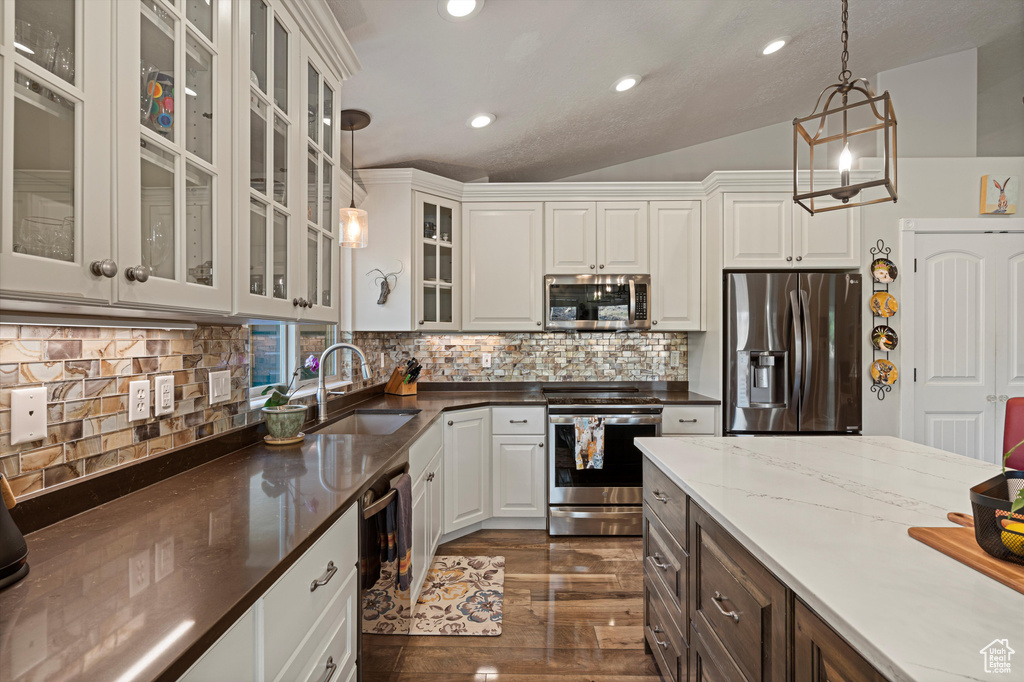 Kitchen with sink, stainless steel appliances, vaulted ceiling, and hanging light fixtures