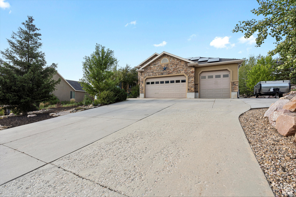 View of front of home featuring solar panels and a garage