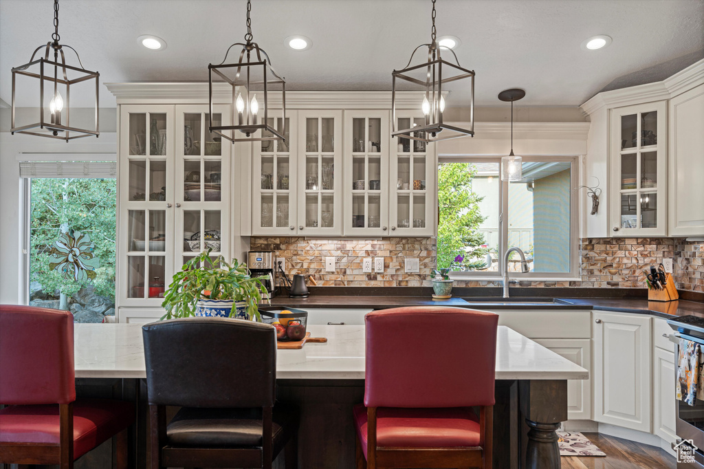 Kitchen with white cabinets, pendant lighting, backsplash, sink, and a breakfast bar area