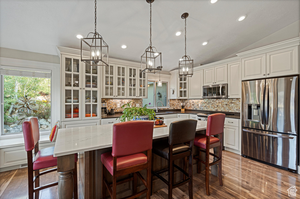 Kitchen featuring decorative backsplash, white cabinets, vaulted ceiling, stainless steel appliances, and sink