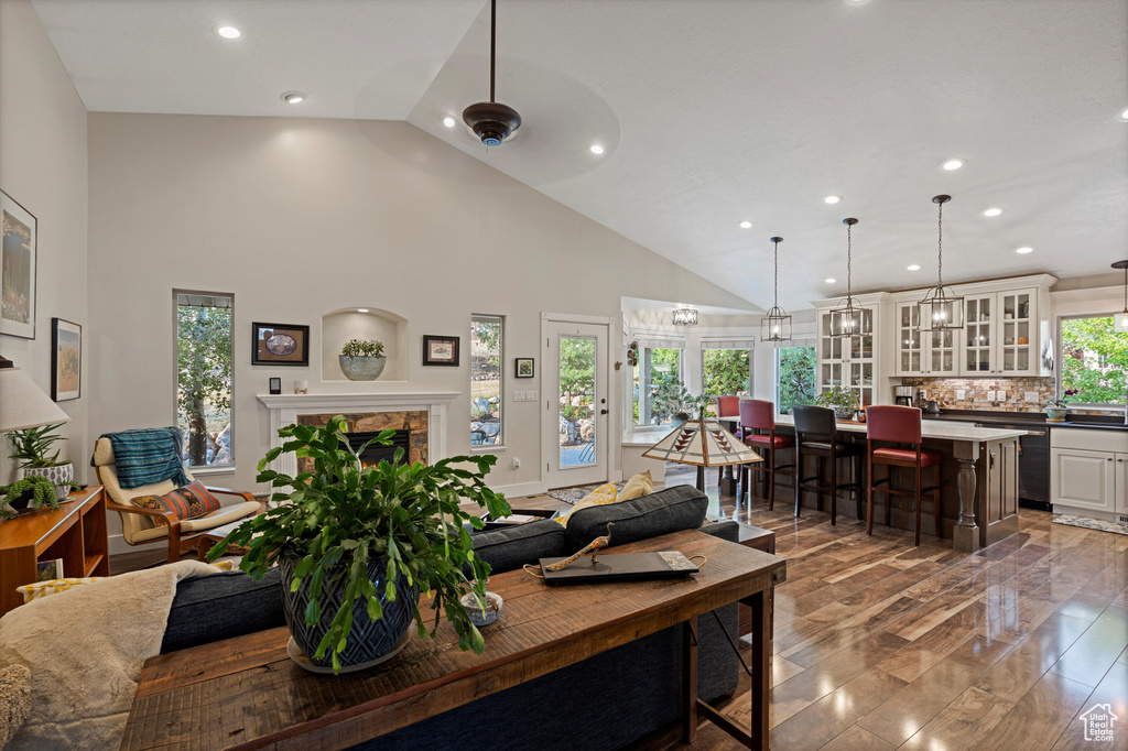 Dining room featuring high vaulted ceiling, a fireplace, hardwood / wood-style flooring, and ceiling fan