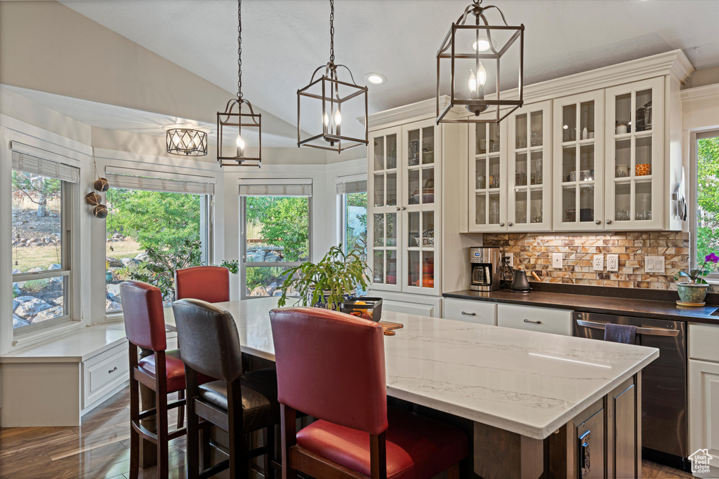 Kitchen featuring lofted ceiling, white cabinets, and a healthy amount of sunlight