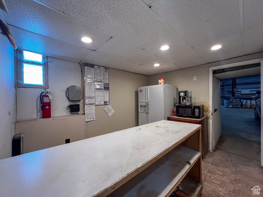 Kitchen with a drop ceiling, white refrigerator with ice dispenser, and tile patterned flooring