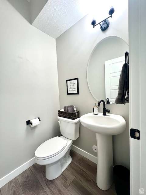 Bathroom featuring wood-type flooring, a textured ceiling, and toilet