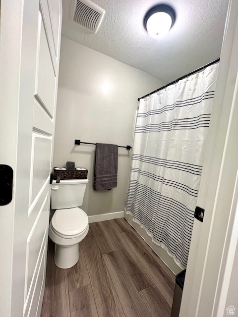 Bathroom featuring a textured ceiling, toilet, and wood-type flooring