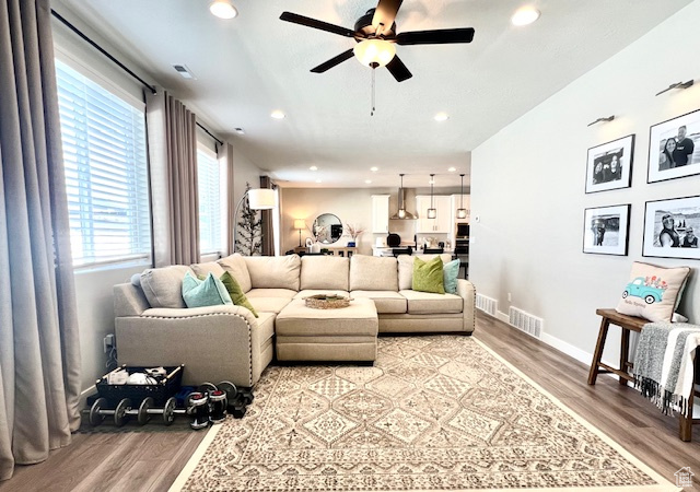 Living room with ceiling fan and light hardwood / wood-style flooring