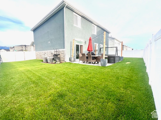 Rear view of house with a patio, cooling unit, and a lawn